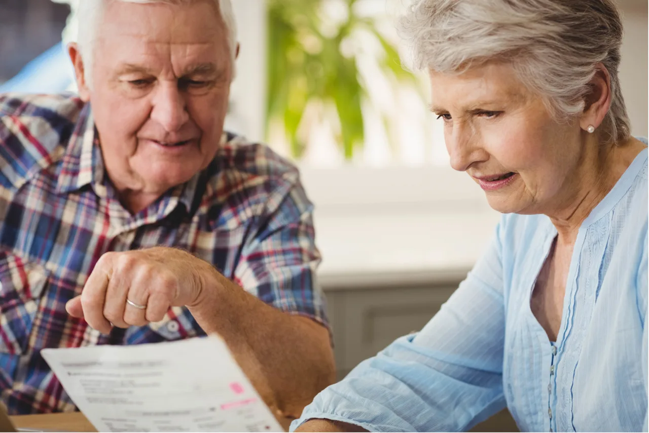 Two older adults reviewing paperwork together at a table